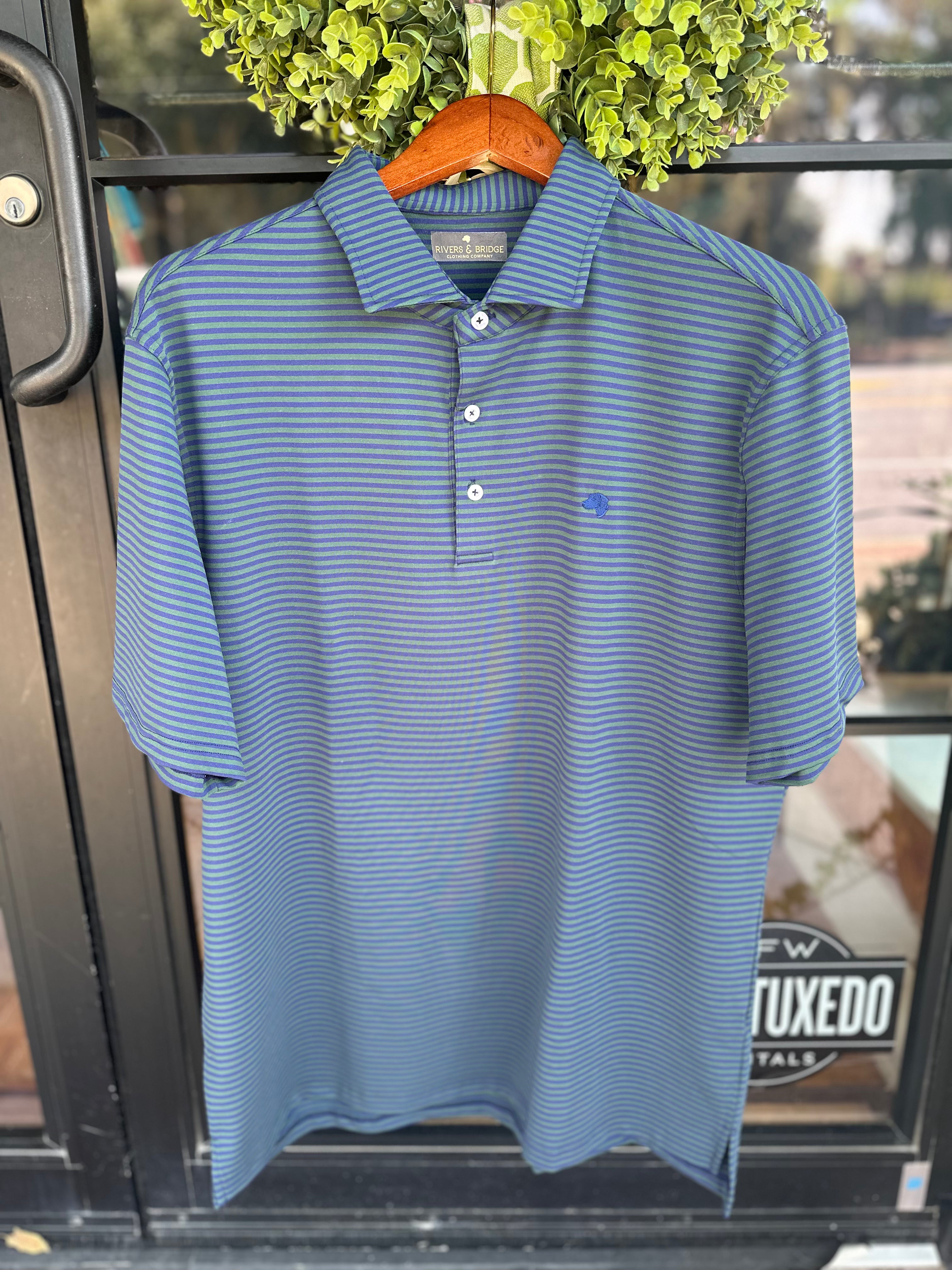 Hunter green and navy striped performance polo with Rivers & Bridge Clothing Company banding. There is a navy lab embroidered on the left chest.