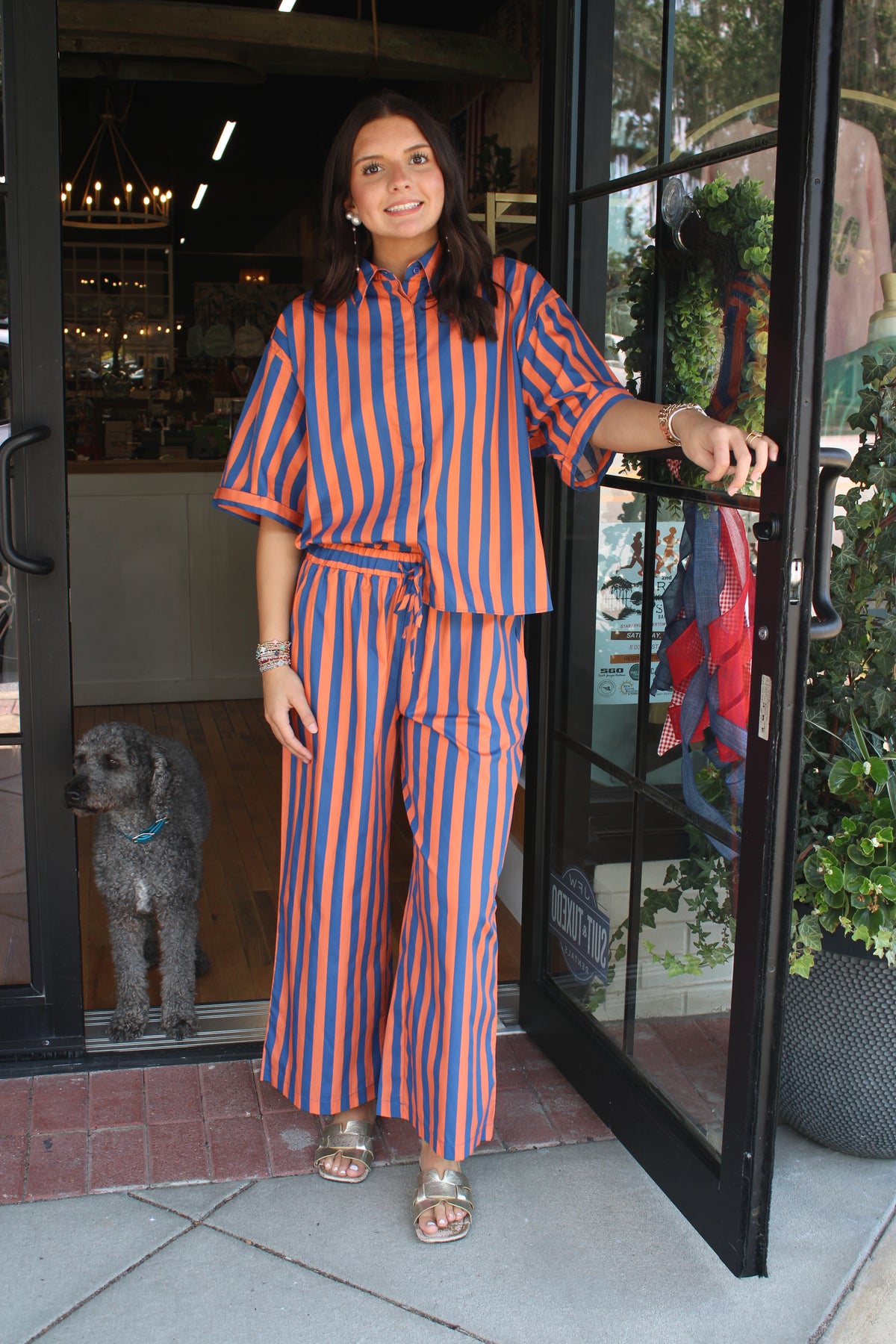 A woman wearing a matching orange and blue vertically striped short-sleeve top and wide-leg pants set.