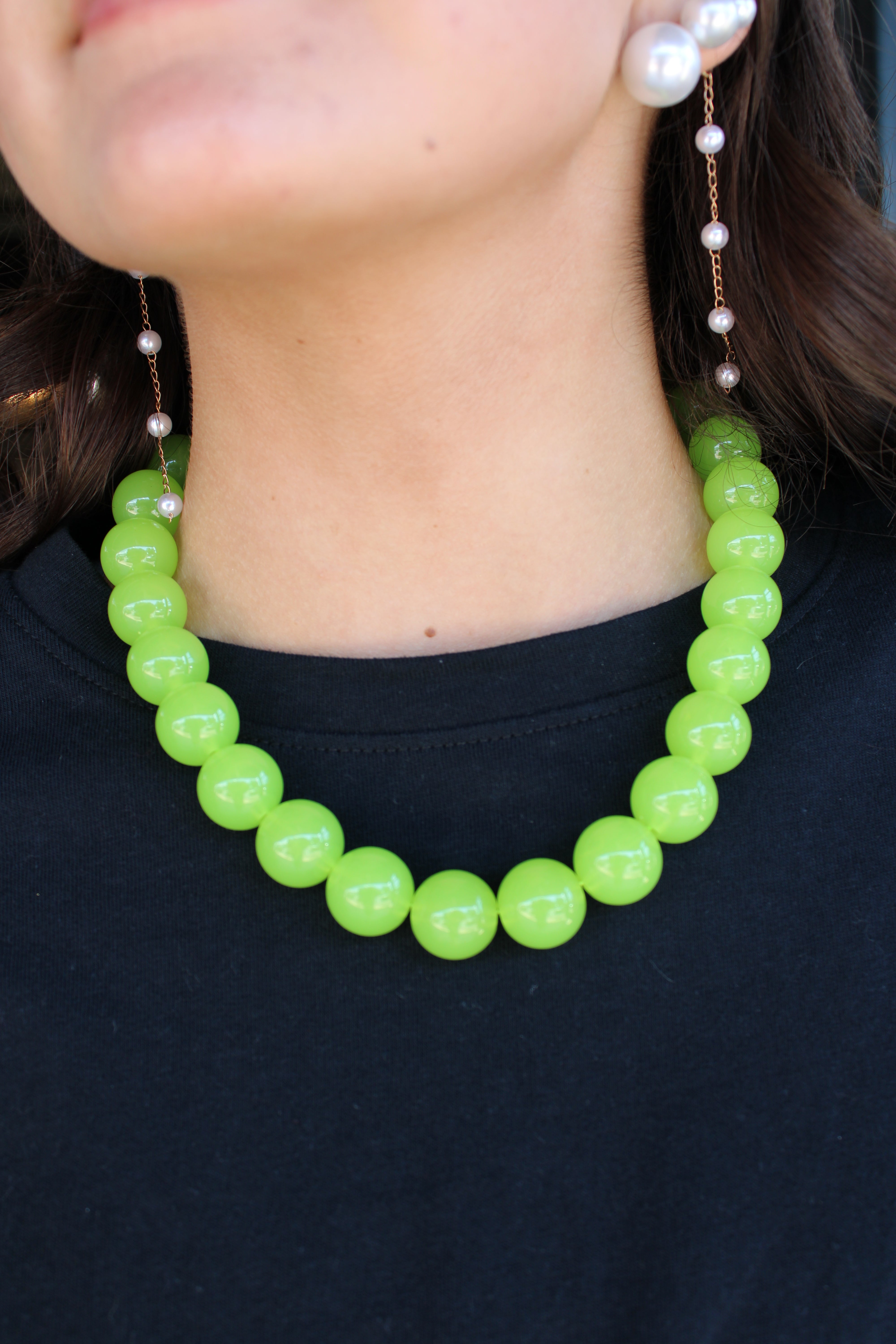 A close-up of a person wearing a chunky lime green beaded necklace