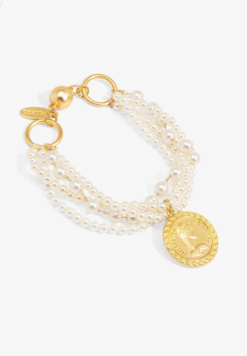 A gold-tone multi-strand pearl bracelet featuring a round gold coin pendant and a magnet clasp, displayed on a clean white background.