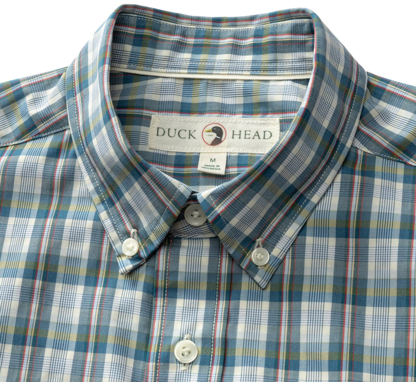 A close-up of a Duck Head plaid button-down shirt in blue, white, and red, showing the collar, buttons, and inner neck label.