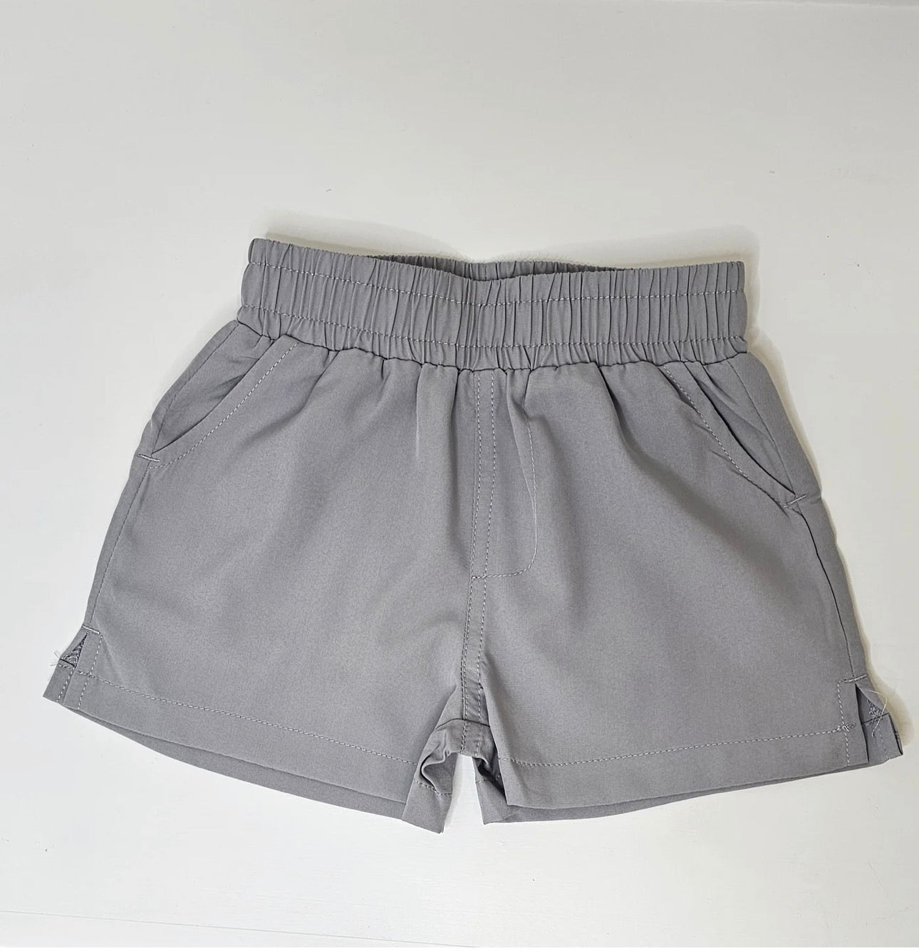 A pair of light gray elastic-waist shorts with side pockets, laid flat on a white background.