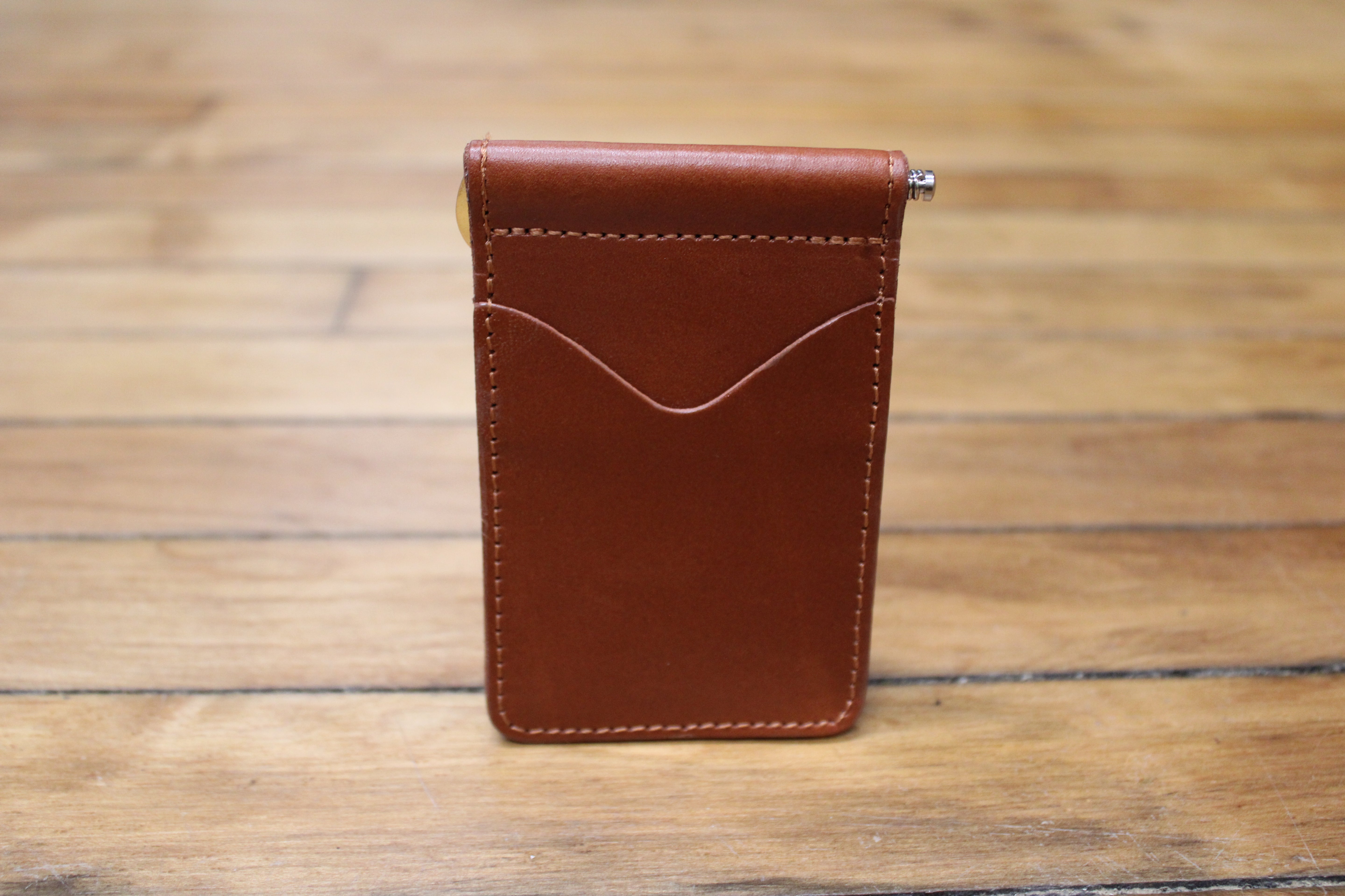A brown leather front pocket wallet with a curved front slip pocket