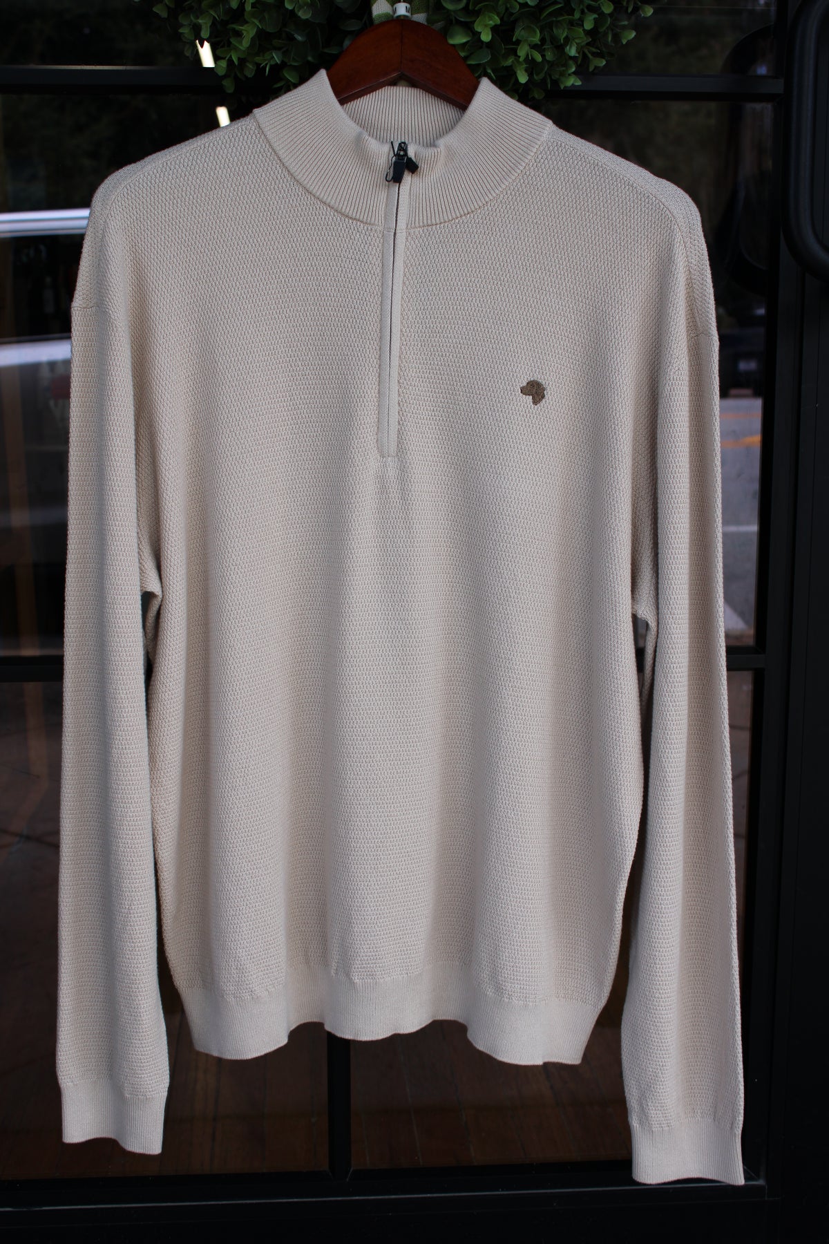 oatmeal colored pullover with brown dog logo on the left chest