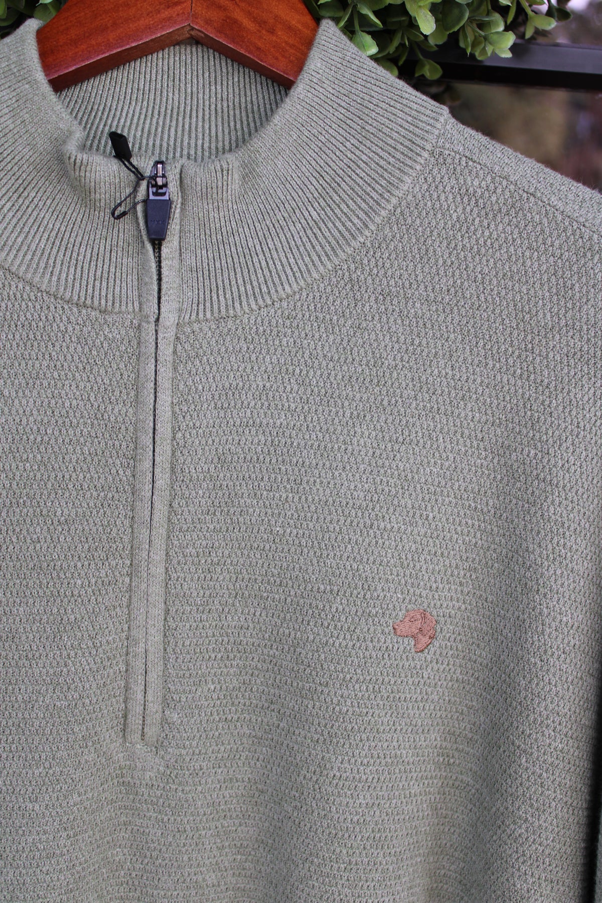 close up of a brown dog logo on an olive colored pullover