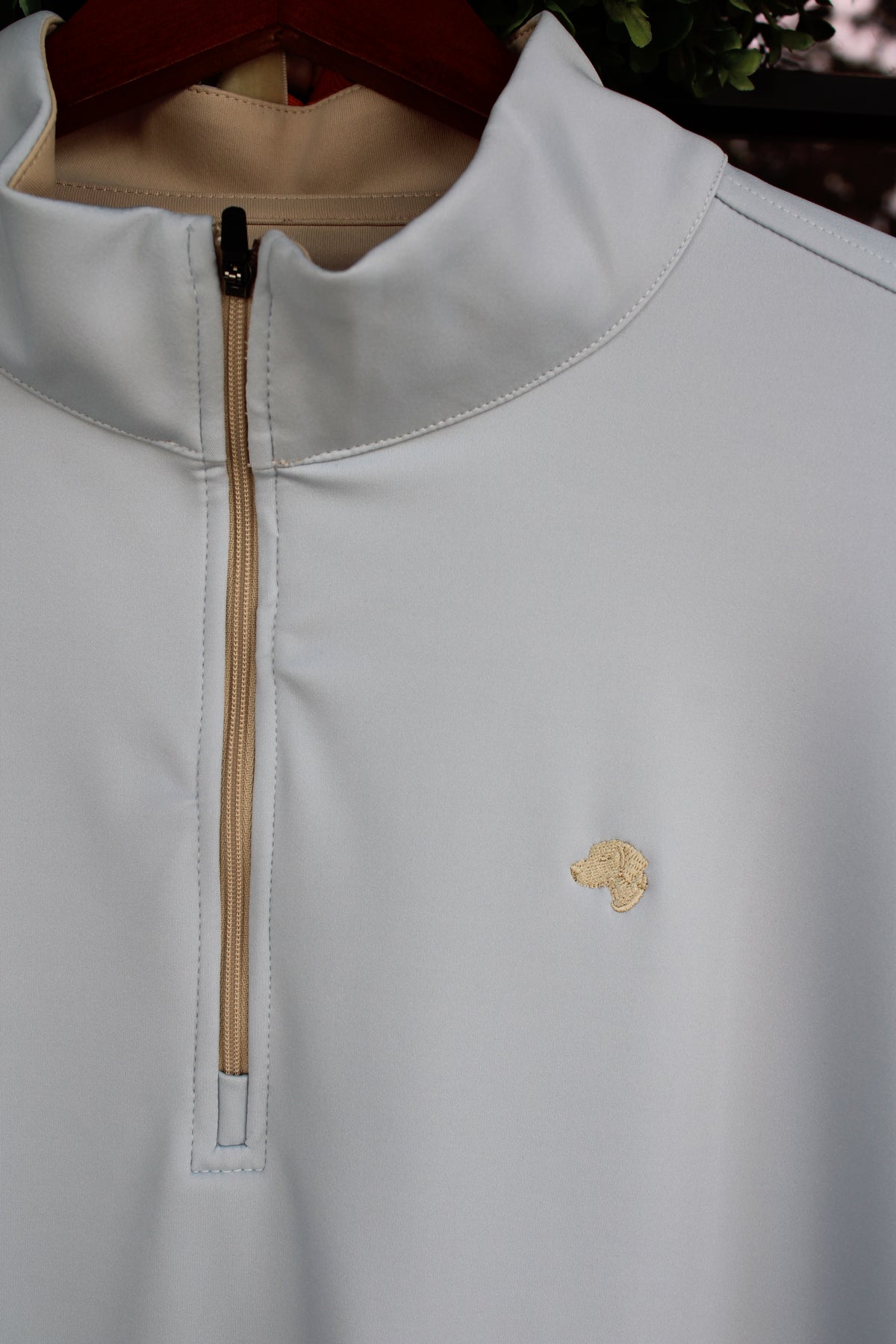 close up of cream colored zipper and dog logo on a light blue pullover