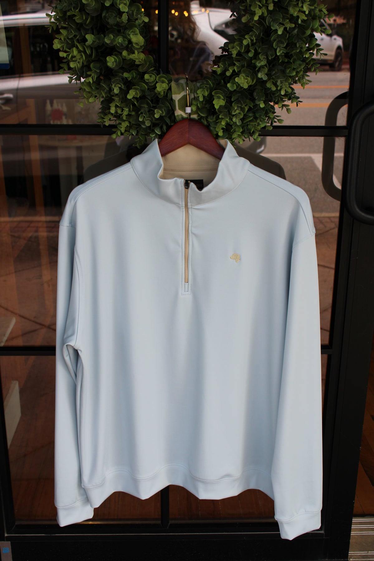 light blue pullover with cream colored dog logo on left chest and cream colored zipper
