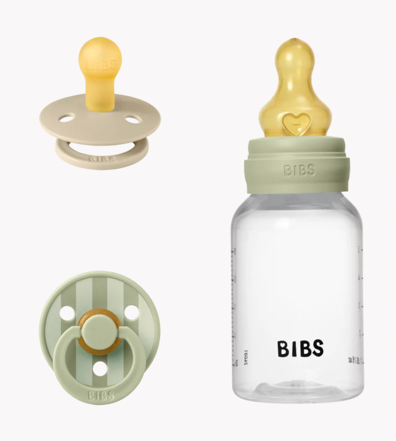 Bibs baby bottle and pacifier set on a light gray background, featuring a clear bottle with a pale green collar, yellow teat, and black measurement markings, alongside two pacifiers in beige and pale green with yellow accents.