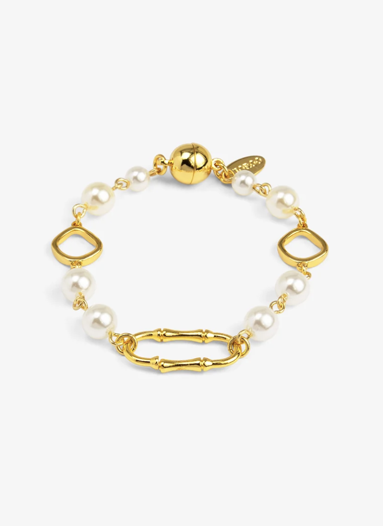 A gold and pearl bracelet featuring white freshwater pearls, gold geometric links, a bamboo-style link, and a polished gold ball magnet clasp, shown on a light gray background.