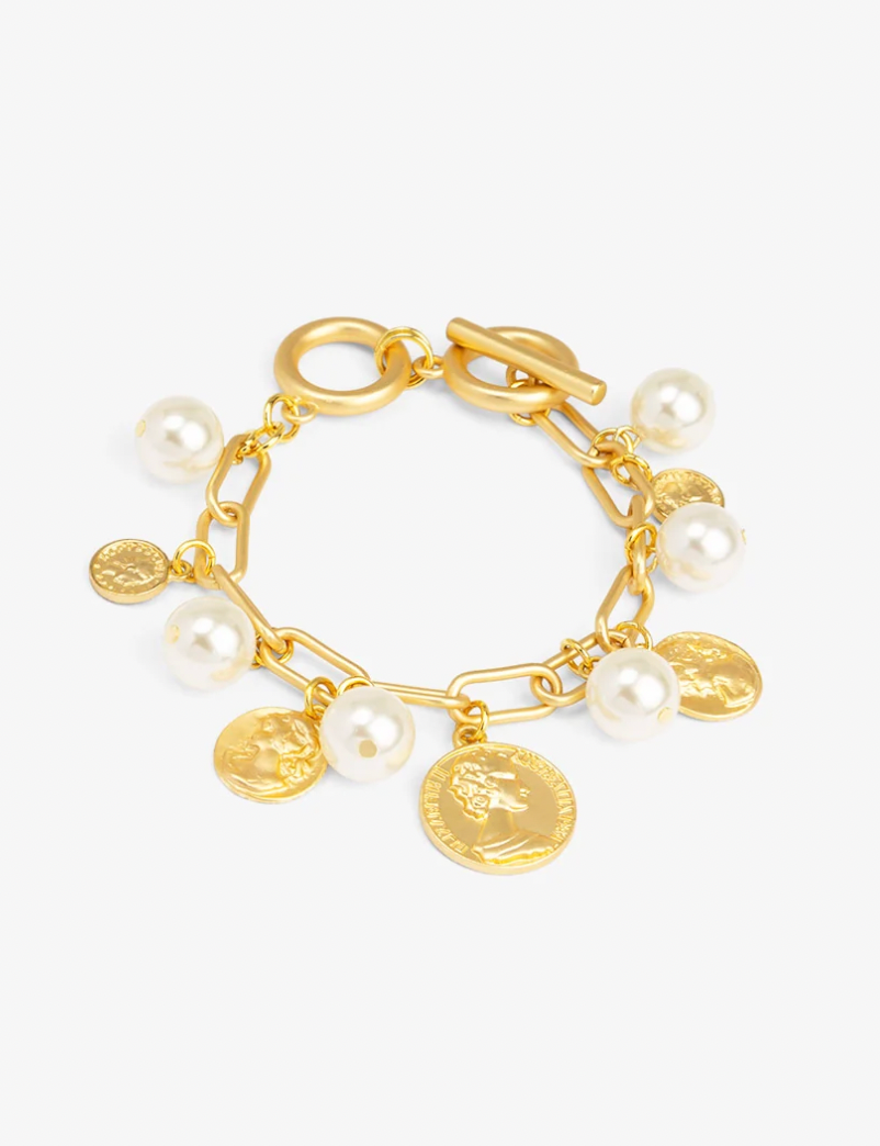 A gold-tone charm bracelet featuring a toggle clasp, a chain link base, and dangling charms including faux pearls and gold coin charms, shown on a light gray background.