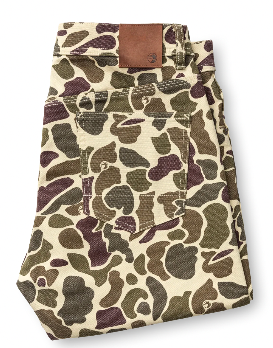 A pair of folded pants featuring a classic camouflage pattern in olive green, dark brown, and beige, with a brown leather patch on the waistband, shot against a plain white background.