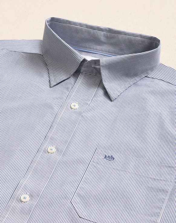 A close-up of a men's dress shirt with a fine blue and white vertical stripe pattern, featuring a classic pointed collar, white buttons, and a single chest pocket with a small embroidered logo.