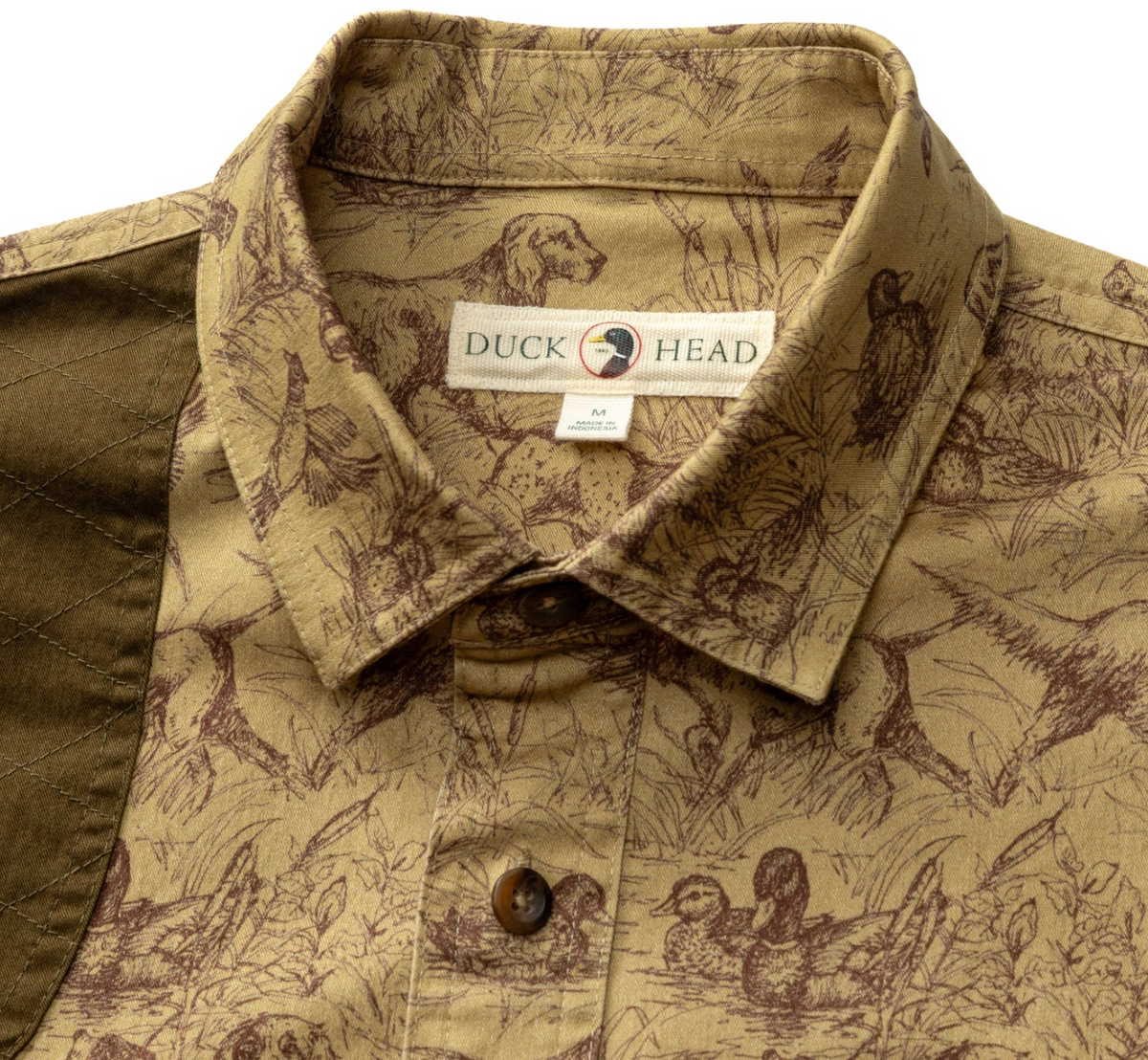 Close-up of a Duck Head button-down shirt collar and upper chest area, featuring a tan and brown wildlife print with duck, deer, and bird illustrations. The inner neck label clearly shows the Duck Head brand.