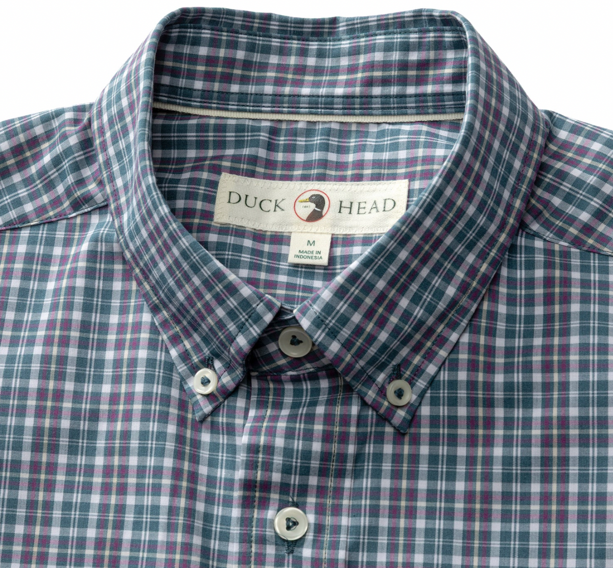 Close-up of a Duck Head men's plaid button-down shirt in a muted blue-gray, purple, and white pattern, showing the collar, brand label, and front buttons.
