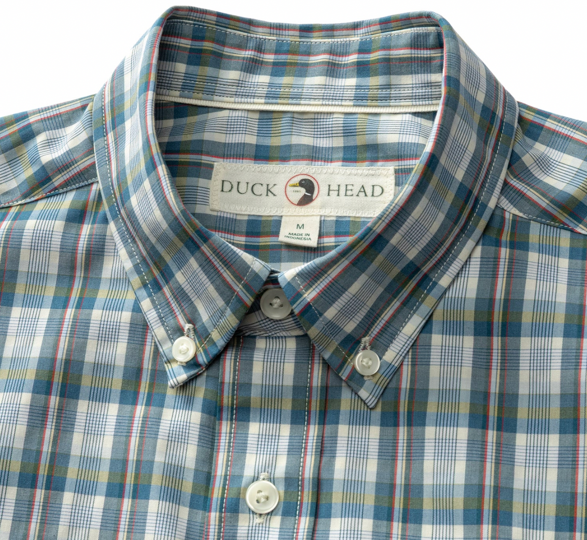 A close-up of a Duck Head plaid button-down shirt in blue, white, and red, showing the collar, buttons, and inner neck label.