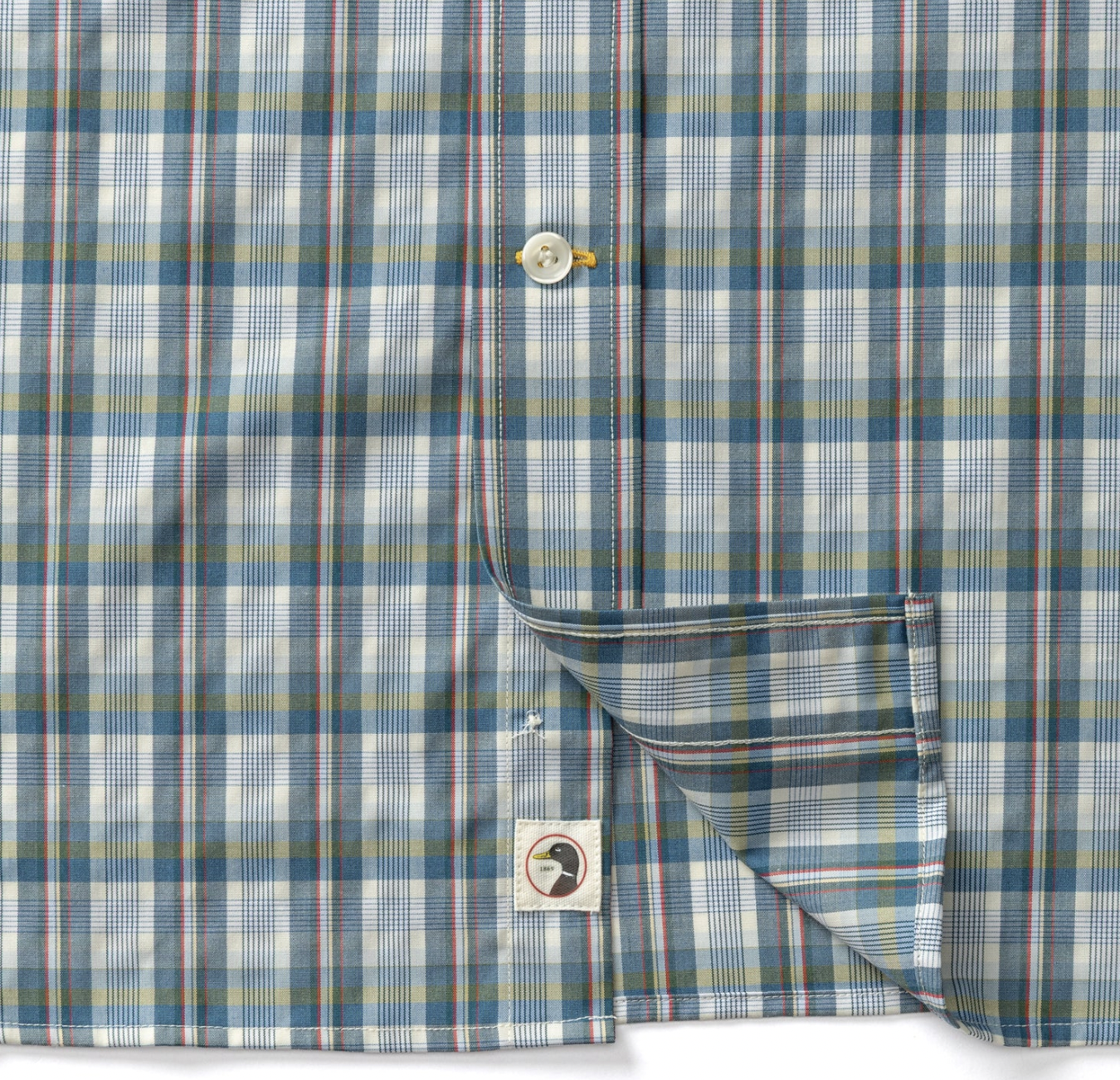 Close-up of a plaid button-up shirt in blue, white, and muted red with thin yellow stripes, showing the collar, button, and a folded cuff pocket.
